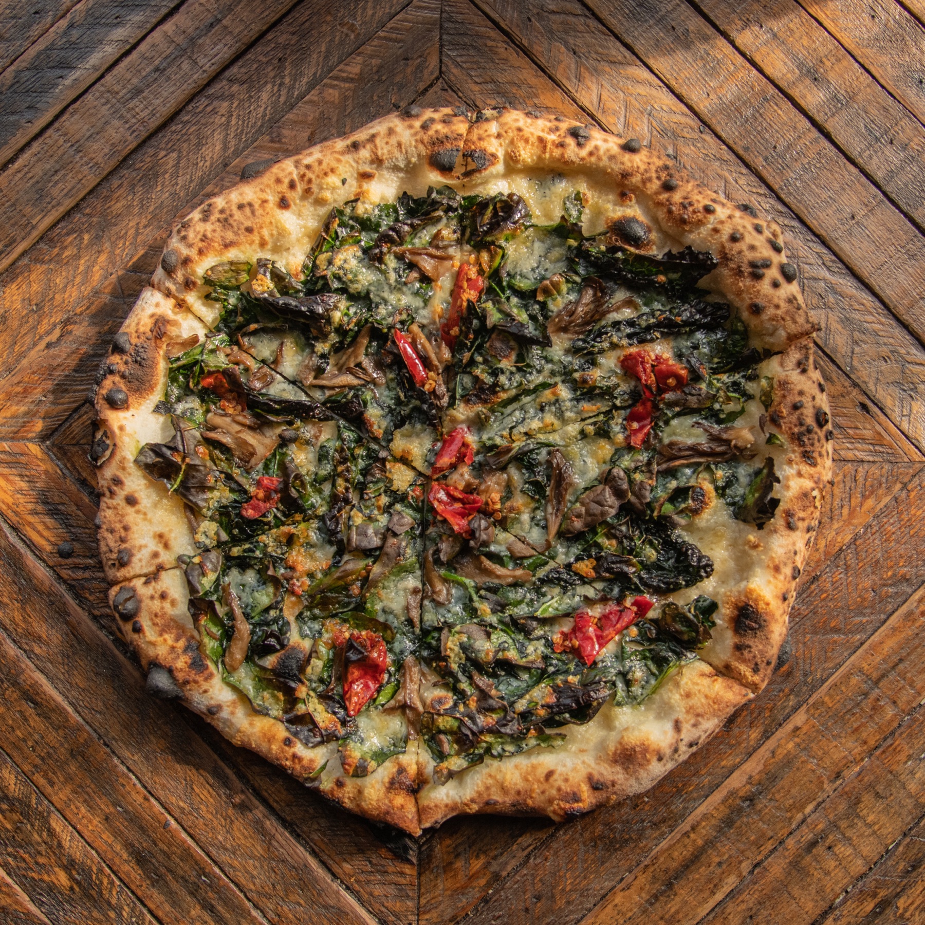 Wood-fired pizza with greens and roasted tomatoes