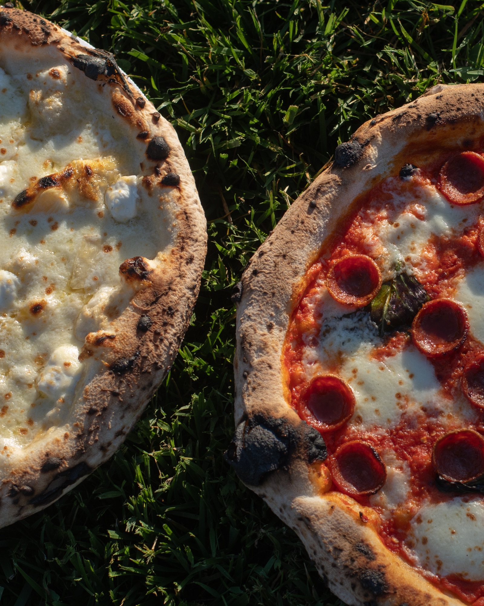 Two wood-fired pizzas from above — white and pepperoni